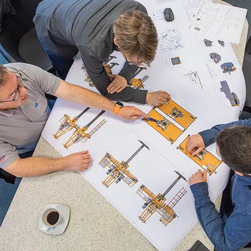 Ingenieurteam bespricht technische Zeichnungen und Konstruktionspläne für industrielle Anlagen bei Storm Anlagenbau