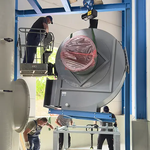 Montageteam positioniert ein gro&szlig;es Aggregat mit Kran und Arbeitsb&uuml;hne w&auml;hrend einer Hatec Industriemontage mit Fokus auf flexible Arbeiten vor Ort und pr&auml;zises Einbringen schwerer Bauteile