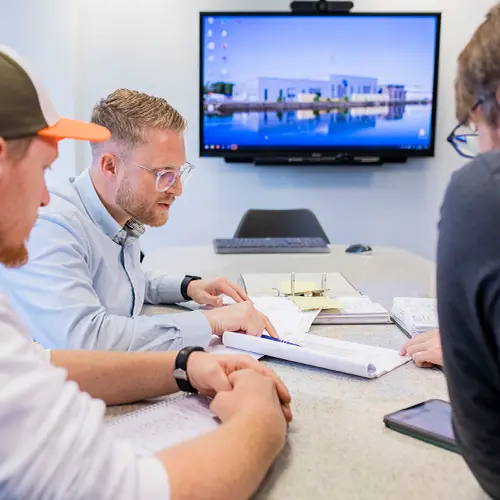 Team bespricht technische Pl&auml;ne in einem Besprechungsraum bei Hatec Industriemontagen mit Fokus auf genaue Projektvorbereitung Vermessung und Abstimmung komplexer Arbeitsabl&auml;ufe