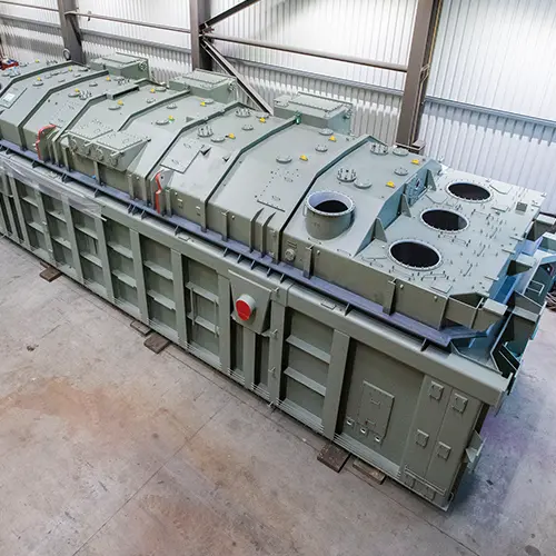 Gro&szlig;es Maschinengeh&auml;use f&uuml;r industrielle Anlagenfertigung von Hatec Industriemontagen komplett vormontiert in der Halle mit sichtbaren &Ouml;ffnungen und Verst&auml;rkungselementen auf massivem Stahlrahmen