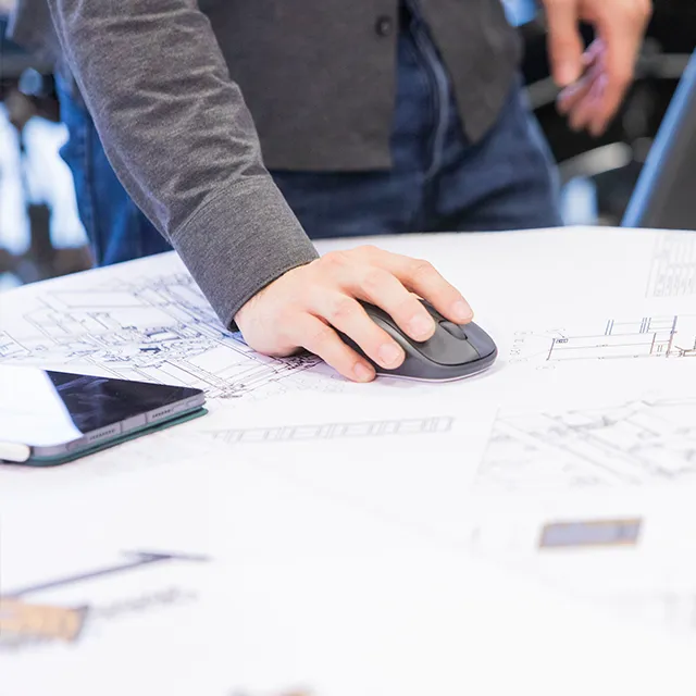 Planungsarbeit an technischen Zeichnungen mit Computermaus und Unterlagen bei der Storm GmbH