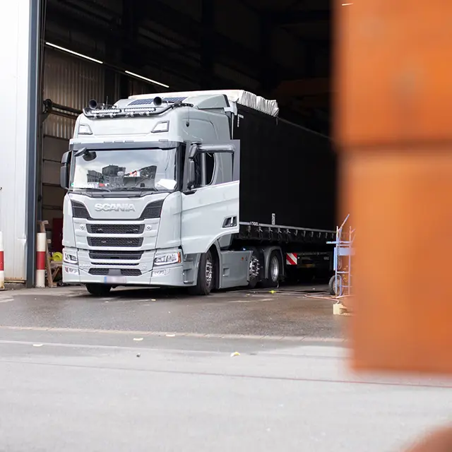 Lastwagen fährt aus einer Industriehalle und zeigt den Bereich Logistik und Warenabwicklung eines Industriebetriebs