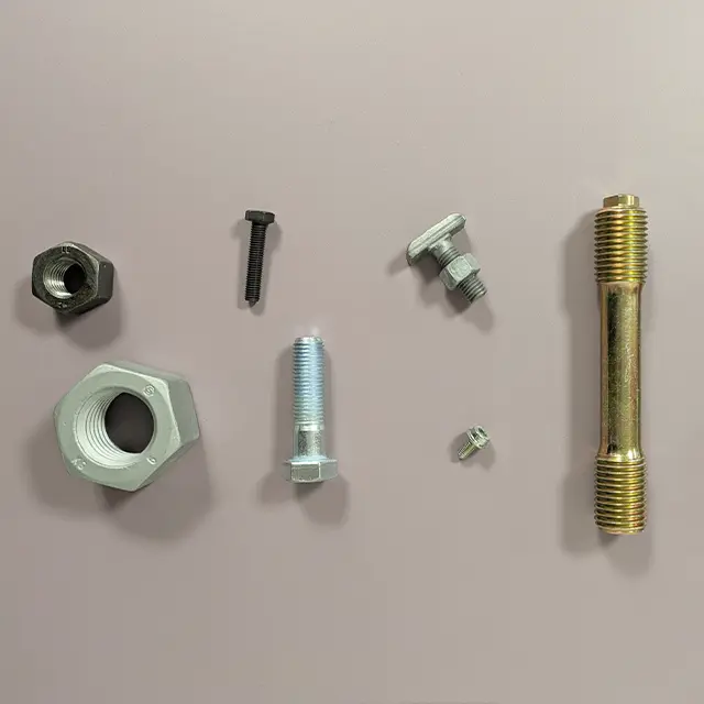 Verschiedene Verbindungselemente wie Schrauben Muttern und Gewindebolzen vor neutralem Hintergrund in übersichtlicher Anordnung