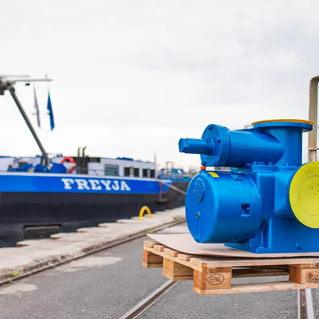 Industrielle blau lackierte Maschinenkomponente auf einer Palette am Hafen mit einem Schiff im Hintergrund als Beispiel f&uuml;r technische Komponenten f&uuml;r Schiff und Industrie von Hatec Handel