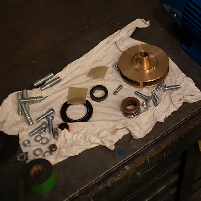 Einzelne Metallteile Dichtungen Schrauben und eine Armaturenkomponente liegen f&uuml;r Wartungsarbeiten auf einem Tuch auf einer Werkbank als Beispiel f&uuml;r Brandschutzarmaturen und Service bei Hatec Handel